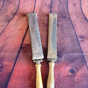 Peut inclure: Deux cuirs à rasoir anciens avec manches en bois. Les cuirs ont une surface rectangulaire en cuir fixée à une poignée en bois avec une garniture métallique. Les manches sont de couleur jaune clair et le cuir est gris foncé.