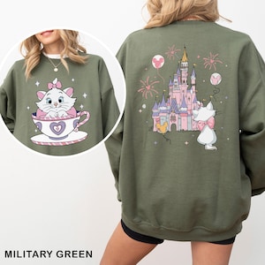 A green sweatshirt with a cartoon image of a cat in a teacup and a castle on the back.