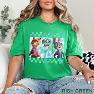 May include: Irish green t-shirt featuring three cartoon characters: a fox in a pink shirt, a blue snake, and a rabbit in a blue jacket. The design is framed by a checkered pattern. The text "IRISH GREEN" is at the bottom.