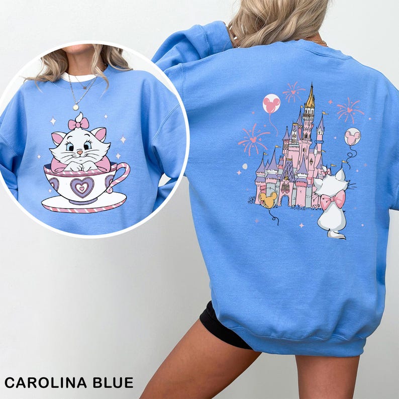 A person wearing a blue sweatshirt with a cartoon image of a cat in a teacup and a castle on the back.