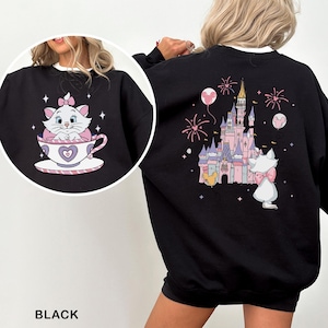 A black sweatshirt with a pink and white cat and a castle on it, along with fireworks in the background.