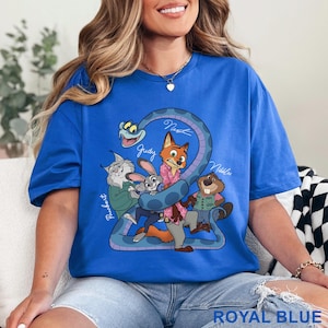 May include: Royal blue t-shirt featuring a cartoon graphic of characters from a movie. The graphic includes a snake and several animal characters with names written above them. The text "ROYAL BLUE" is at the bottom.