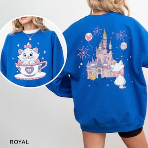 A person wearing a blue sweatshirt with a cartoon image of a cat and a castle on the back.