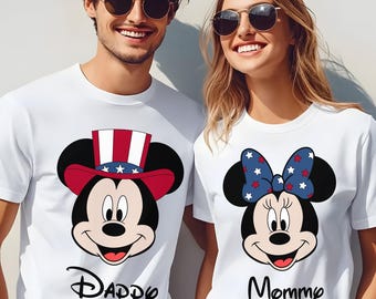 May include: White t-shirts with Mickey and Minnie Mouse designs. One shirt features Mickey Mouse in a patriotic hat with the word "Daddy" below. The other shirt has Minnie Mouse with a bow and the word "Mommy".