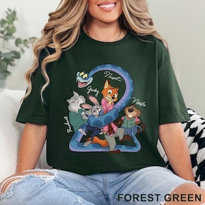 May include: Forest green t-shirt featuring a cartoon graphic of characters from a movie. The graphic includes a blue snake, a fox, a rabbit, a beaver, and a cat. The text "FOREST GREEN" is printed at the bottom of the shirt.