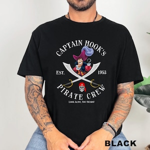 May include: Black t-shirt featuring a Captain Hook's Pirate Crew design. The graphic includes an illustration of Captain Hook, crossed swords, and the text "EST. 1953". The phrase "LOOK ALIVE, YOU SWABS!" is also included.
