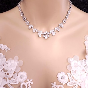 May include: A silver necklace with a floral design featuring clear cubic zirconia stones.