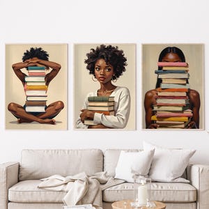 May include: Three framed art prints featuring illustrations of women with stacks of books. One print shows a woman sitting cross-legged with a book stack, another shows a woman holding books, and the third shows a woman with books covering her face.
