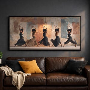 May include: A framed artwork depicts five dancers in flowing dresses, captured mid-movement against a backdrop of muted colors. The dancers are in various poses, with arms raised, creating a sense of grace and motion. The artwork is displayed above a brown leather sofa.