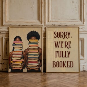 Peut inclure: Deux affiches encadrées. L'affiche de gauche montre deux personnes tenant de hautes piles de livres colorés devant leur visage. L'affiche de droite présente le texte marron foncé SORRY, WE'RE FULLY BOOKED sur un fond beige clair.