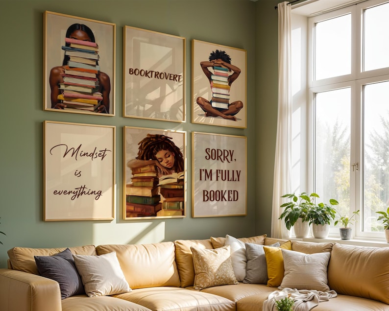May include: A selection of framed art prints with images of people and books, alongside motivational quotes. The prints are displayed on a green wall above a tan sofa. The art has gold frames.