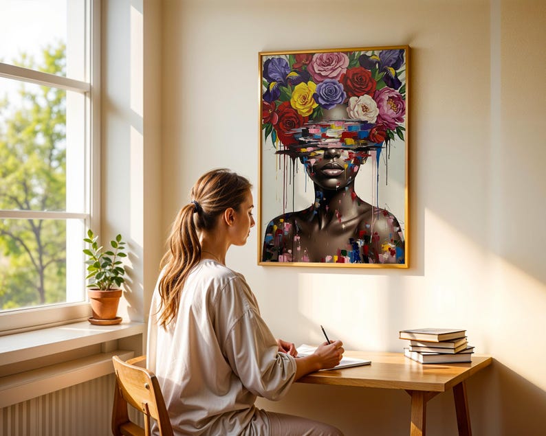 May include: A framed artwork shows a woman with a floral headdress of roses in various colours. The woman's face is partially obscured by colourful brushstrokes. The artwork is displayed on a wall above a wooden desk.