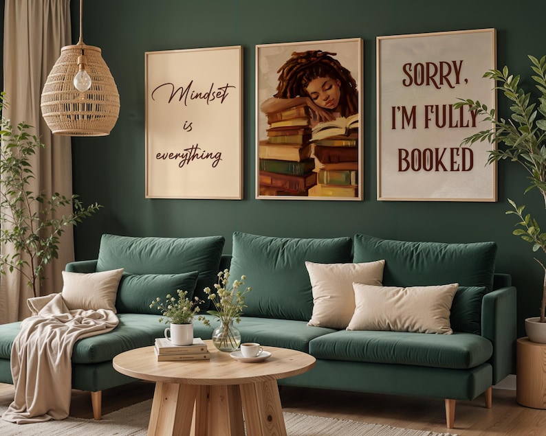May include: A living room with three framed prints, one reading 'Mindset is everything', another showing a woman sleeping on books, and the third saying 'Sorry, I'm fully booked'. The room has a green sofa, beige cushions, and a wooden coffee table.