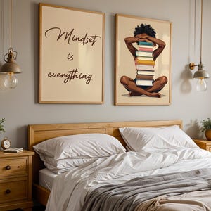 May include: Two framed art prints hang above a bed. One print reads "Mindset is everything" in script. The other depicts a person with a stack of books. The bedroom has wooden furniture and pendant lights.