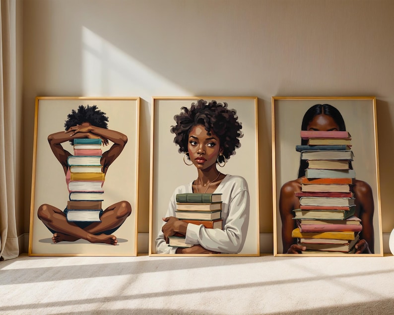 May include: Three framed art prints featuring illustrations of Black women with stacks of books. One woman sits cross-legged with a book stack covering her face. Another holds a stack, and the third has books in front of her face.