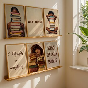 May include: Five framed art prints with a literary theme. The prints feature illustrations of people with books, and text that reads "BOOKTROVERT", "Mindset is everything", and "SORRY, I'M FULLY BOOKED". The frames are light brown.