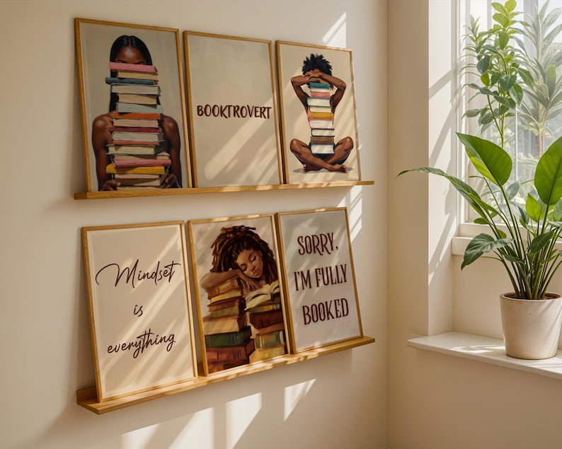 May include: Five framed art prints with a literary theme. The prints feature illustrations of people with books, and text that reads "BOOKTROVERT", "Mindset is everything", and "SORRY, I'M FULLY BOOKED". The frames are light brown.