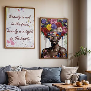 May include: Two framed art prints. One displays the text "Beauty is not in the face, beauty is a light in the heart." The other shows a woman with a floral headpiece. Both are in wooden frames and hang above a grey sofa with cushions.