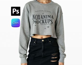 May include: A gray cropped sweatshirt with long sleeves and the text "NOXANIMA MOCKUPS" in black. The model is wearing a black denim skirt. The image also includes the Photoshop and Canva logos.