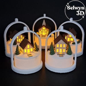 May include: Five illuminated miniature houses with brown roofs and white walls are displayed. Each house is surrounded by a white arch and sits on a white base with small green trees. The houses have lit windows, creating a warm glow. The text "Selwyn 3D" is in the upper right corner.