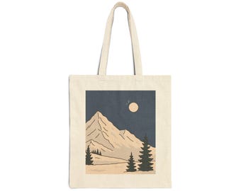 以下が含まれることがあります： クリーム色のトートバッグ。山の風景のデザインが特徴です。イラストは、満月と松の木の下の濃い青色の空の下にある雪をかぶった山を描いています。バッグには、持ち運び用の長いハンドルが2つ付いています。