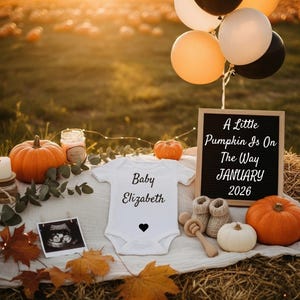 Peut inclure: Une scène d'annonce de bébé avec un body blanc avec le texte "Baby Elizabeth" et un cœur. Un panneau indique "A Little Pumpkin Is On The Way JANUARY 2026". Citrouilles, ballons, chaussons de bébé et une échographie sont également présents.