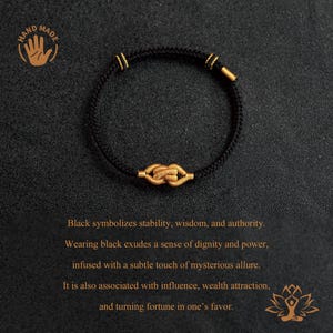 Puede incluir: Pulsera negra con dise&ntilde;o de nudo dorado. La pulsera presenta un cord&oacute;n negro con detalles dorados y un nudo dorado central. La imagen incluye el texto "HAND MADE".