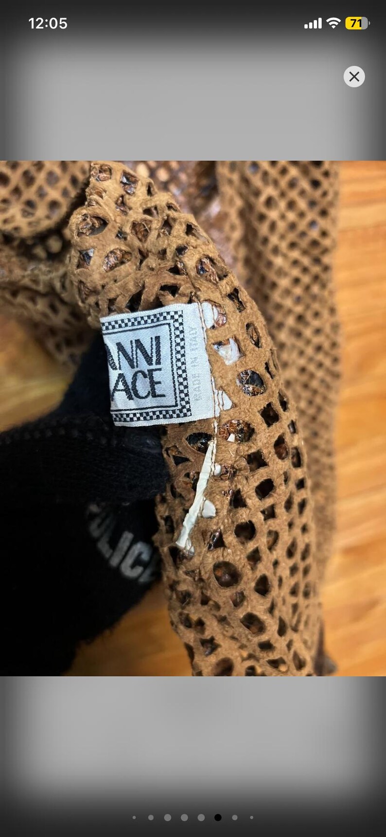 May include: Close-up of a brown, open-weave fabric with a label that reads "ANNI ACE" in a checkered frame. The fabric has a perforated design. The label also says "MADE IN ITALY".