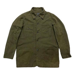 May include: A long-sleeved, olive green work shirt with multiple pockets and a button-up front.