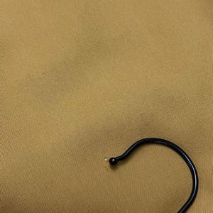 Puede incluir: Primer plano de una tela marr&oacute;n con un gancho de percha de metal negro.
