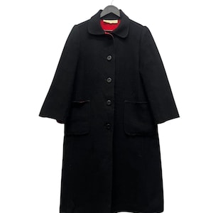 May include: A black coat with a red lining, featuring a classic collar and two front pockets. The coat has a button-down closure and is hanging on a black hanger. The coat's length extends to the mid-calf.