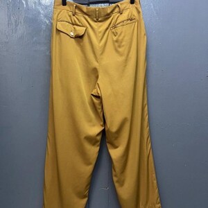 Puede incluir: Un pantal&oacute;n de pierna ancha de color mostaza con un bot&oacute;n en el bolsillo trasero.