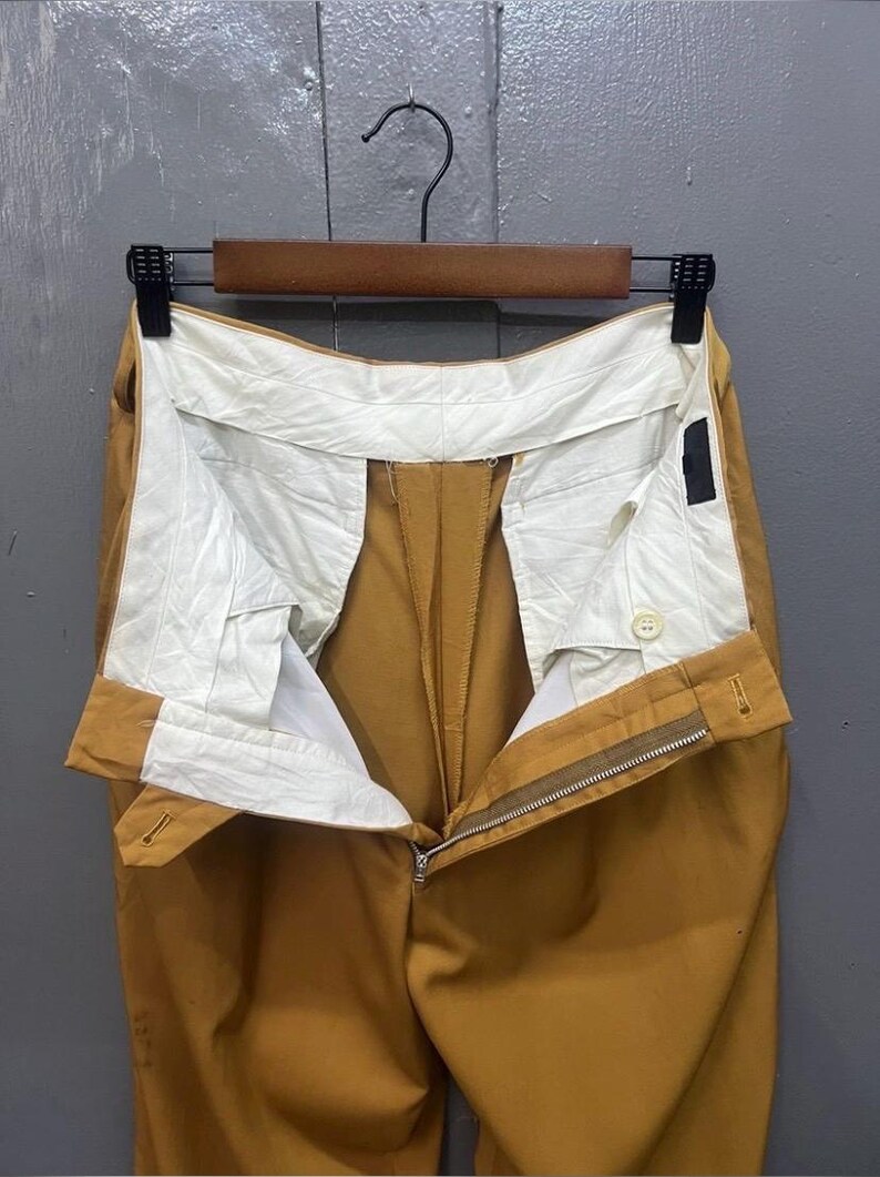 Puede incluir: Un pantal&oacute;n de color amarillo mostaza con cierre de cremallera y bot&oacute;n. El pantal&oacute;n tiene un forro blanco y est&aacute; hecho de una tela lisa.