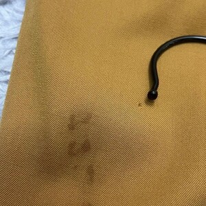 Puede incluir: Primer plano de una tela de color amarillo mostaza con una textura sutil. La tela tiene una mancha oscura en el centro.