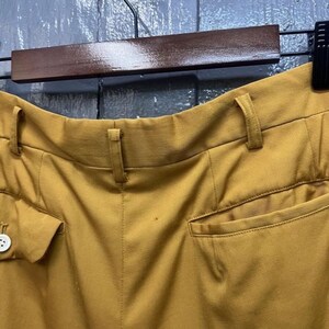Puede incluir: Vista trasera de pantalones de color amarillo mostaza con un bot&oacute;n y un bolsillo en el lado izquierdo y un bolsillo en el lado derecho.