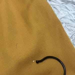 Puede incluir: Primer plano de una tela de color amarillo mostaza con un ligero brillo. La tela es lisa y tiene una textura sutil.