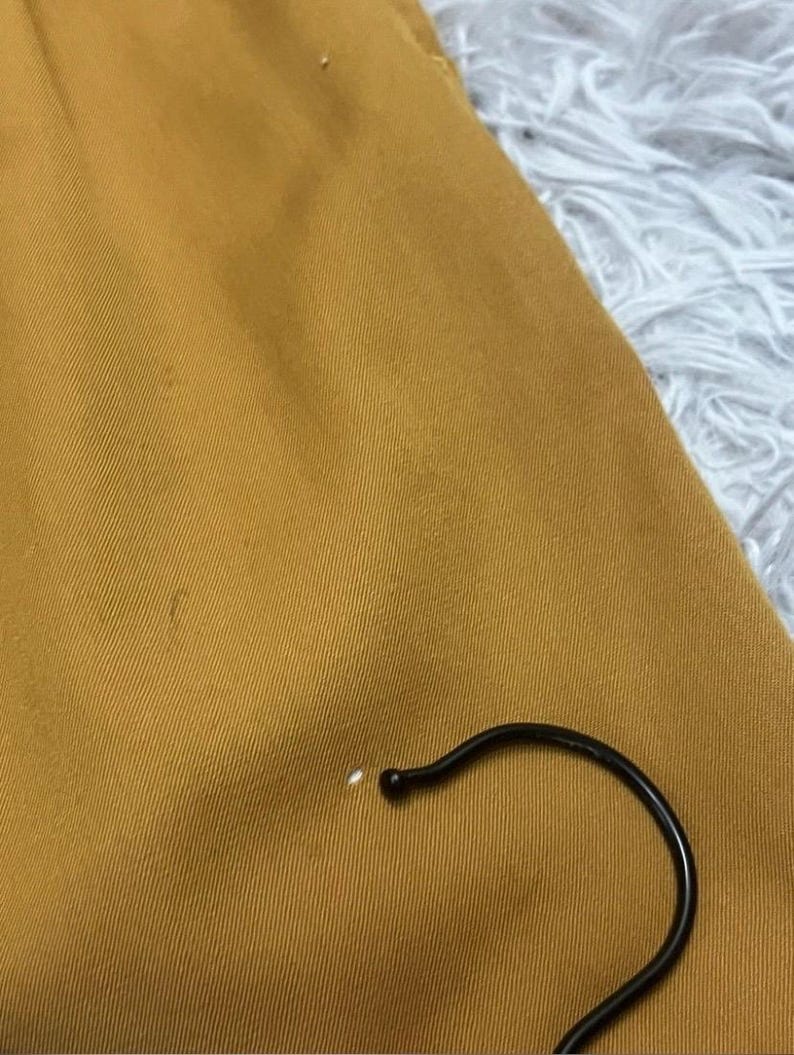 Puede incluir: Primer plano de una tela de color amarillo mostaza con un ligero brillo. La tela es lisa y tiene una textura sutil.