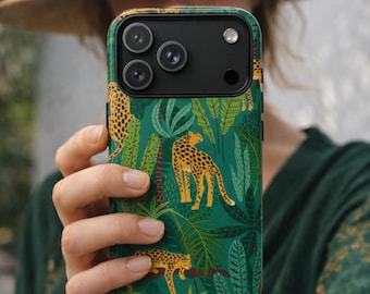 May include: A green phone case featuring a jungle-themed design with yellow leopards and tropical foliage. The case has a black camera module and is held in a person's hand.