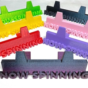 May include: A selection of brightly coloured record dividers, each with the words "NOW SPINNING" printed on them. The dividers are in various colours, including red, yellow, green, black, pink, purple, and a black to purple gradient.