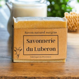 Könnte beinhalten: Eine Seife aus natürlichem, überfettetem Seifen mit einem braunen Papierlabel. Das Etikett lautet "Savon naturel surgras Savonnerie du Luberon Fabriqué en Provence".