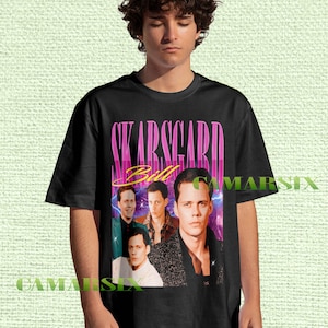 May include: Black t-shirt featuring a collage of images and the name "SKARSGARD" in pink and yellow lettering. The shirt includes multiple images of a person, with the name "Bill" in a cursive font.