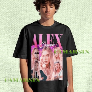 Puede incluir: Camiseta negra con un gráfico rosa de una mujer con pelo largo y rubio, el texto "ALEX Cooper" y varias imágenes de la misma mujer. La camiseta la lleva una persona.