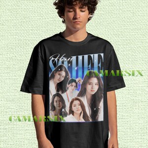 Könnte beinhalten: Schwarzes T-Shirt mit einer Grafik einer Frau mit langen dunklen Haaren. Die Grafik enthält den Namen "Han So Hee" in einer stilisierten Schriftart. Das T-Shirt wird von einer Person getragen.