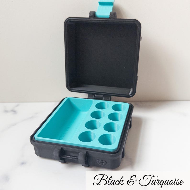 May include: Black and turquoise miniature case, open to reveal a turquoise interior with circular compartments. The case is rectangular with a hinged lid and a clasp closure. The text "Black & Turquoise" is at the bottom.