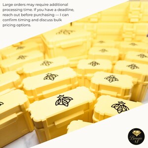 a collection of yellow plastic containers with black bee designs, arranged in rows.