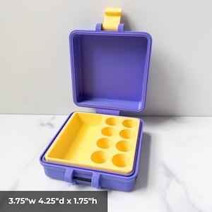 May include: Open purple and yellow plastic container with a yellow interior tray featuring circular cutouts. The container is 3.75" wide, 4.25" deep, and 1.75" high. The lid is open, revealing the interior. The container has a yellow latch.