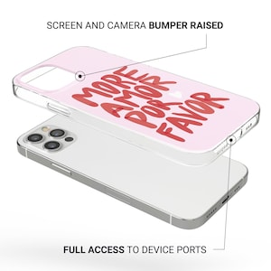 Puede incluir: Una funda de tel&eacute;fono rosa con las palabras "MORE AMOR POR FAVOR" en escritura roja. La funda es transparente en los bordes y se muestra sobre un tel&eacute;fono inteligente plateado. La funda tiene un parachoques de pantalla y c&aacute;mara elevado.