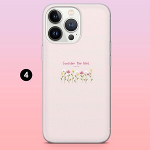 May include: A light pink phone case with a floral design and the text "Consider the lilies." The case features a row of small flowers in yellow, pink, and white. The phone case has a clear camera lens and flash.