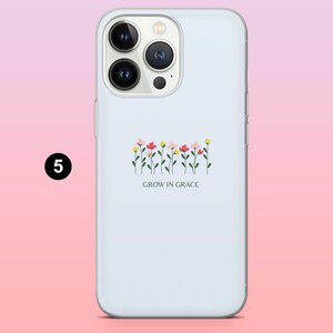 May include: A light blue phone case featuring a floral design with pink, red, and yellow flowers. The phrase "GROW IN GRACE" is printed below the flowers. The case has a glossy finish and a camera cutout.