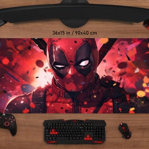 May include: A large rectangular mouse pad featuring a vibrant illustration of Deadpool in a red and black color scheme. The mouse pad measures 36x15 inches. A keyboard, mouse, and controller are visible.
